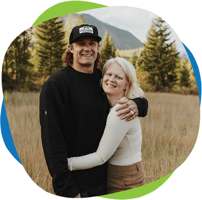 A man and woman hugging in the grass.